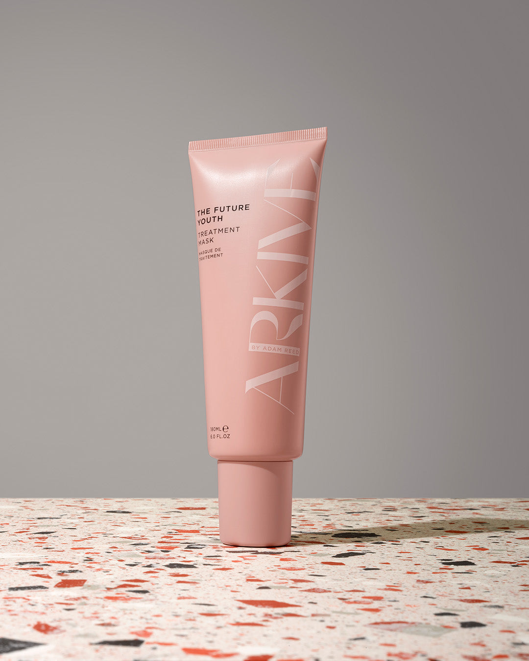 A bottle of Arkive's The Future Youth hair treatment mask on a patterned table