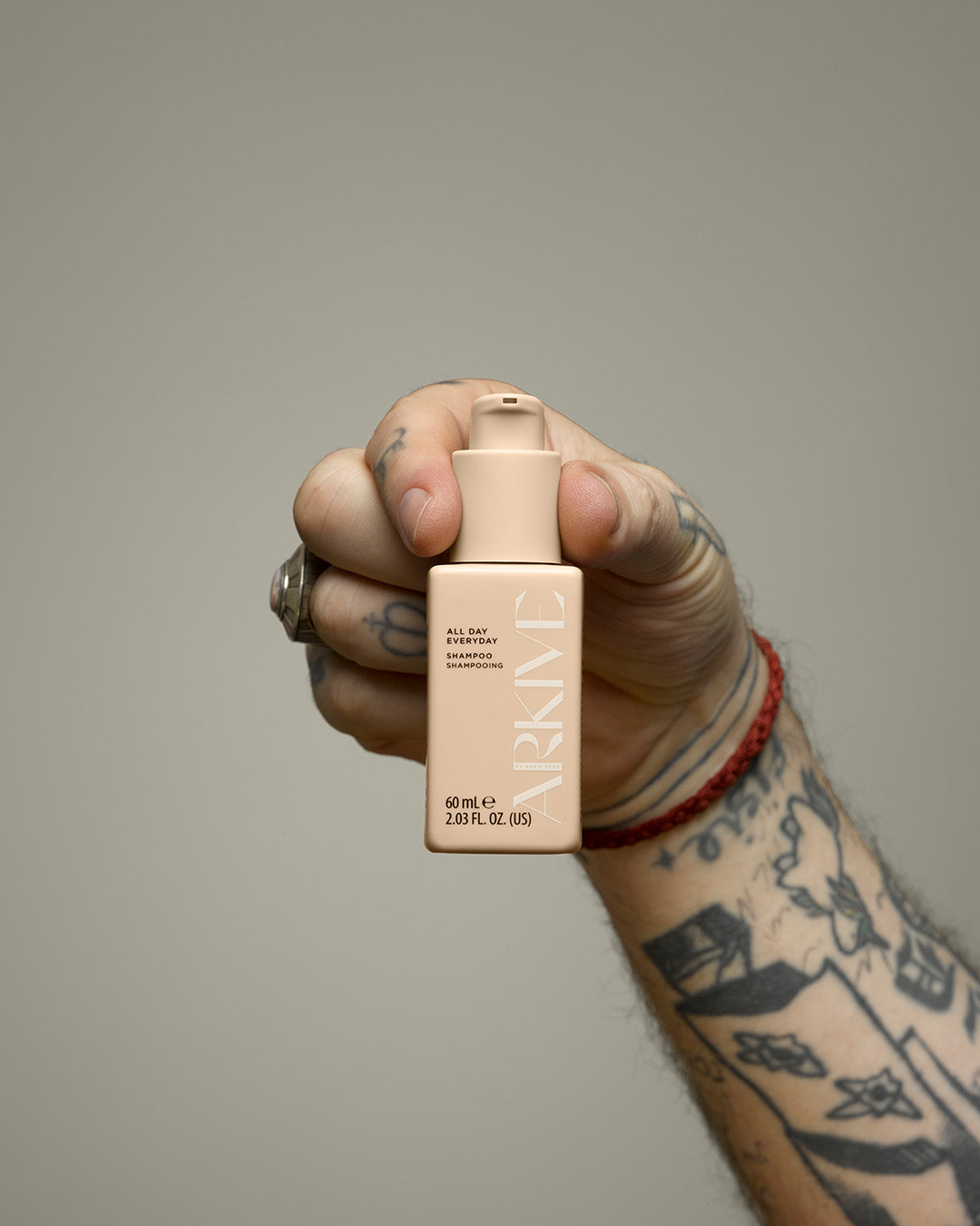 A miniature bottle of Arkive's all day everyday shampoo held against a white background