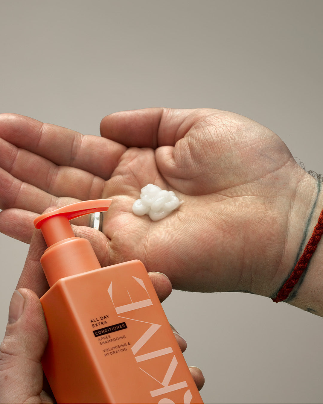 A bottle of Arkive's innovative gel cream conditioner being poured onto an upturned palm