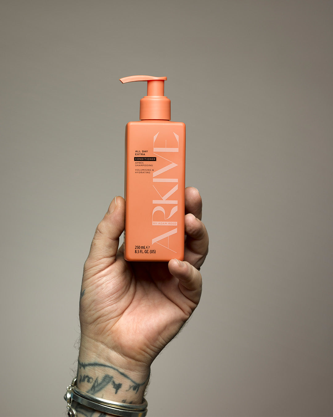 A bottle of Arkive's innovative gel cream conditioner being held up in one hand