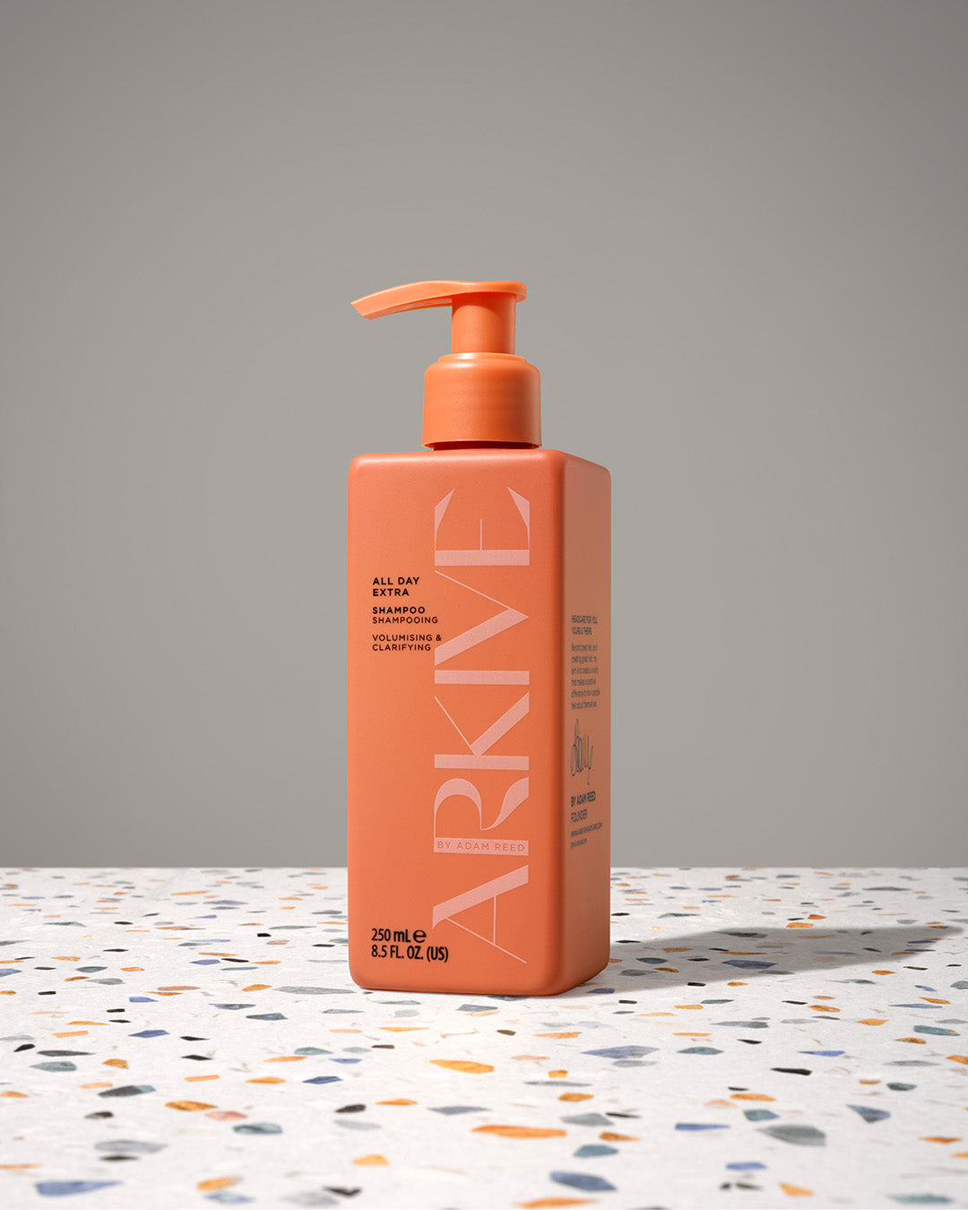 A bottle of Arkive's all day extra shampoo resting on a patterned surface