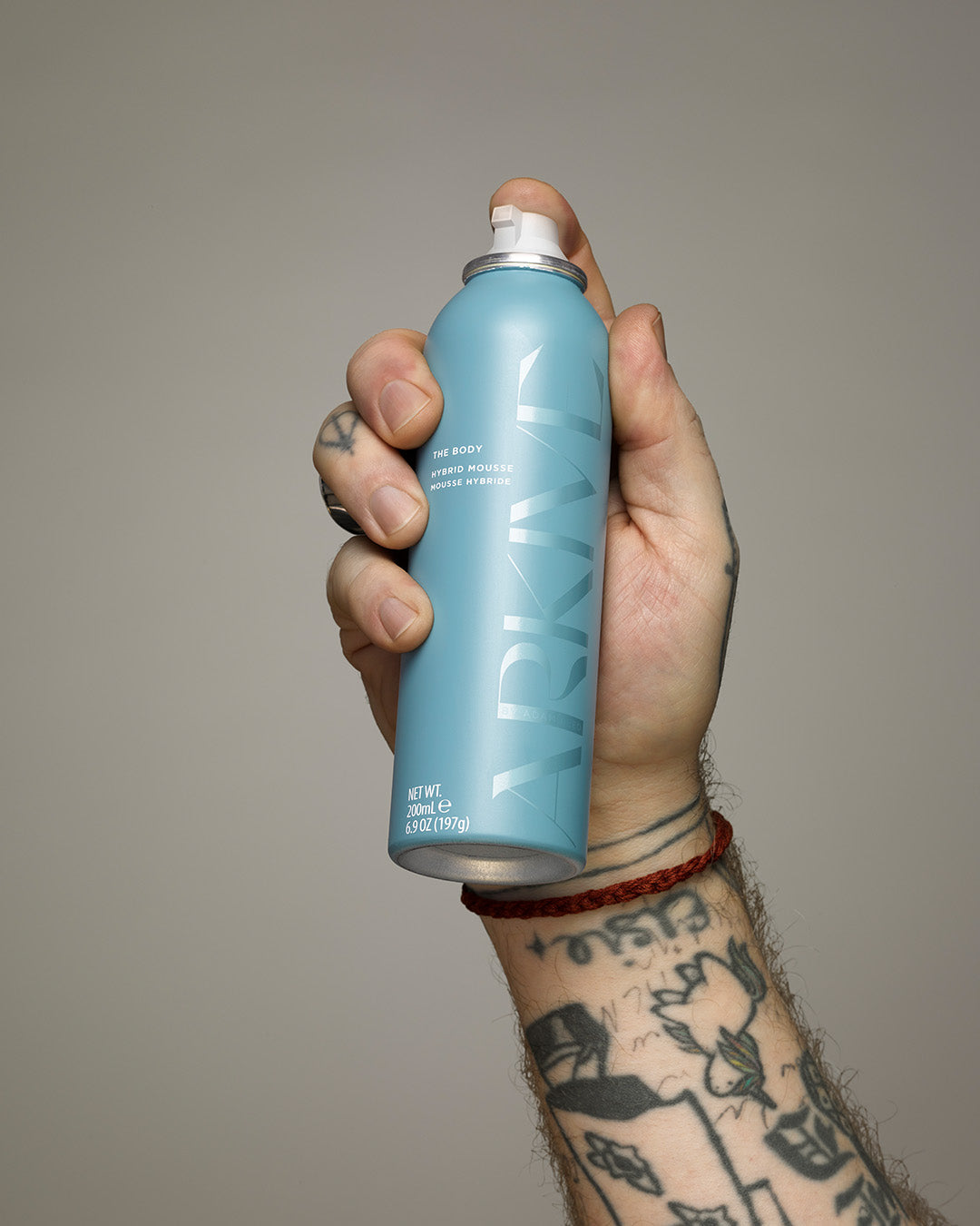 A bottle of Arkive's 'The Body' hybrid hair mousse held in the hand