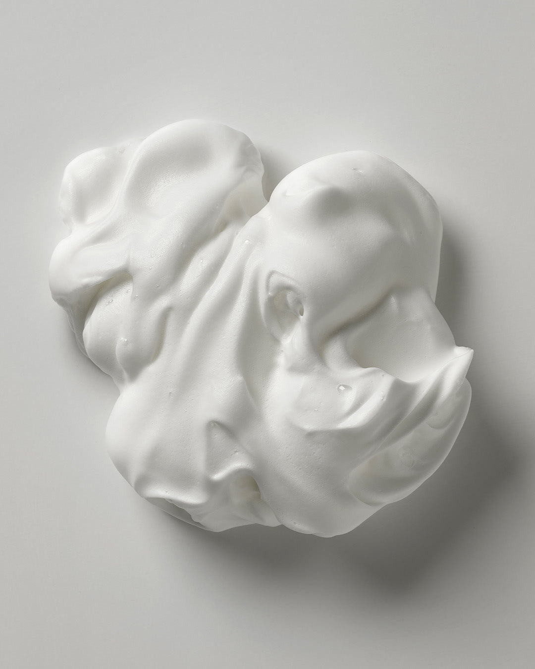 The body hybrid mousse poured onto white surface showing thick fluffy texture