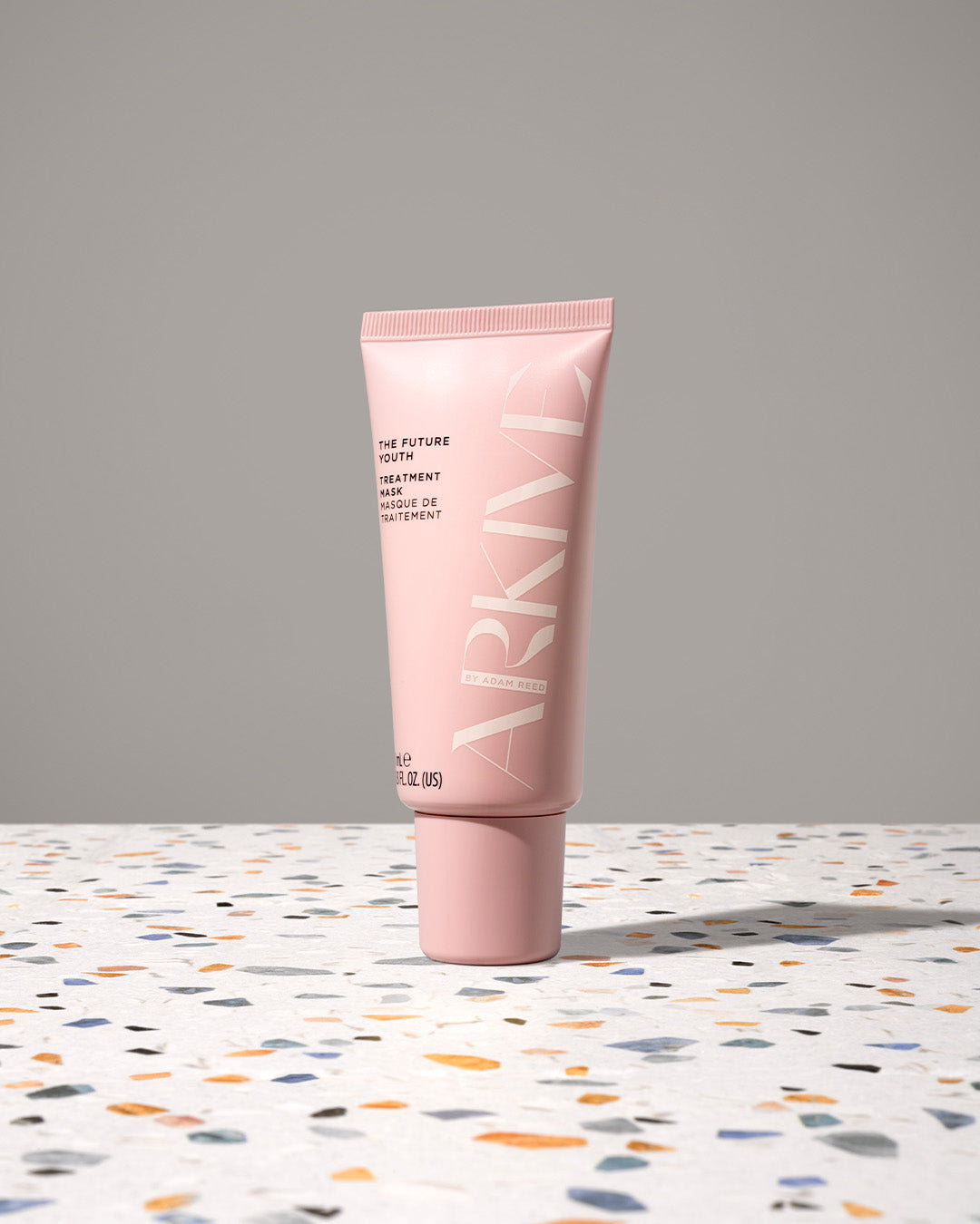 A mini bottle of Arkive's The Future Youth hair treatment mask on a patterned table