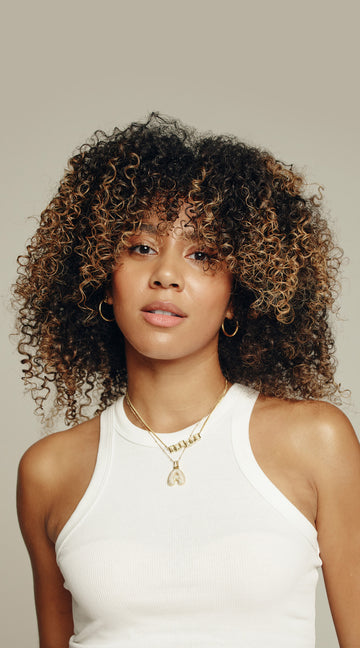 A curly haired model looks into the camera face on